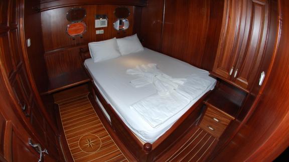 An elegant cabin on the gulet Sahinoğlu, equipped with a comfortable double bed, wooden furniture and porthole windows.